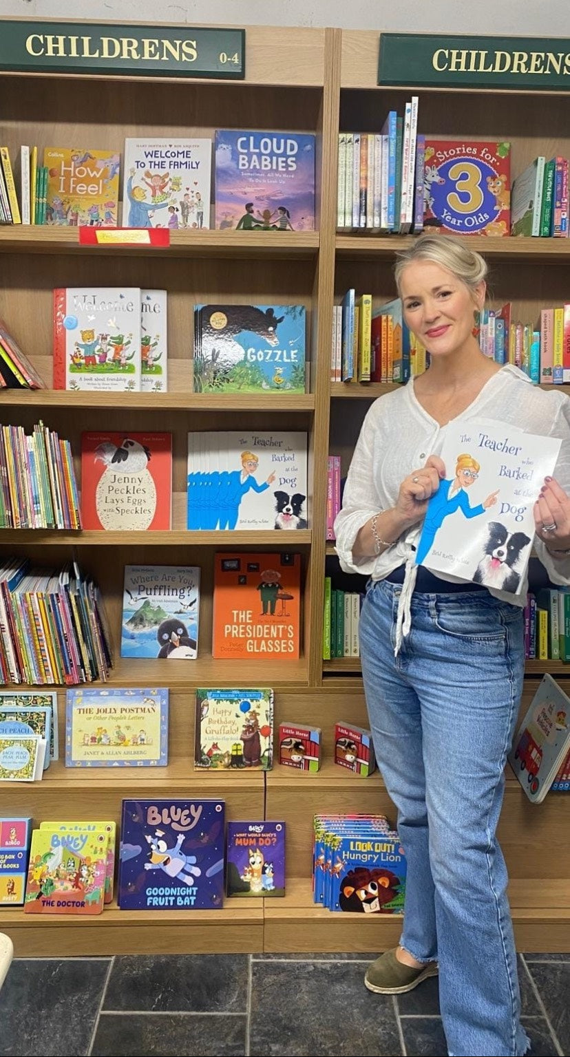 Woman holding a book in front of a bookshelf filled with children's books The teacher who barked at the dog 